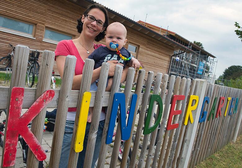 Elisabeth Kudlorz mit ihrem Sohn Toni vor der neuen Kinderkrippe "Frühlingsdorf" in Holzkirchen.
