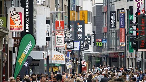 Passanten bummeln auf der Hohen Straße, einer Fußgängerzone in der Kölner Innenstadt.
