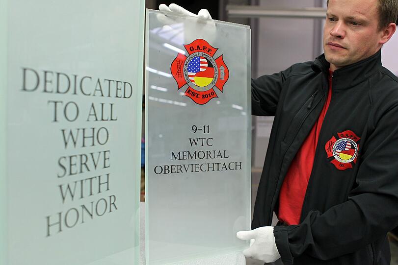 Der 2. Vorstand der "German American Firefighters and Friends", Oliver Süß, inspiziert in Schönsee (Oberpfalz) ein Glaselement des Denkmals der Gemeinde Oberviechtach.
