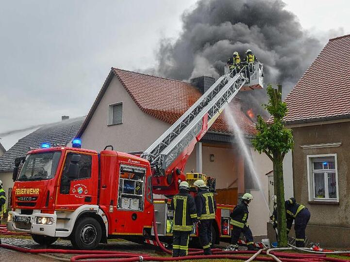 Die Feuerwehr löscht in Leitzkau in Sachsen-Anhalt einen Brand an einem Wohnhaus. Ein Blitz hatte den Dachstuhl in Brand gesetzt.