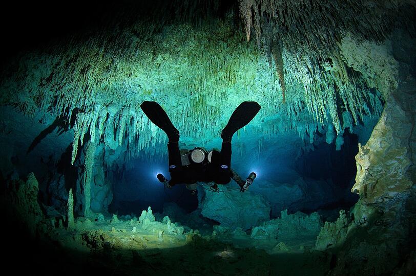 Nichts für schwache Nerven: Uli Kunz umgeben von Tropfsteinen beim Tauchen in einer niedrigen Höhle.