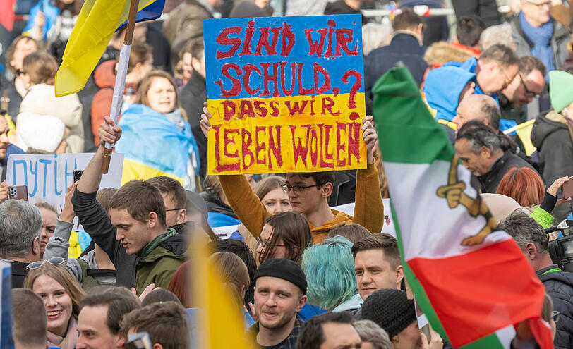 Ein junger Mann aus der Ukraine hält ein Transparent in der Menge hoch. Für ihn und seine Landsleute geht es ums pure Überleben.