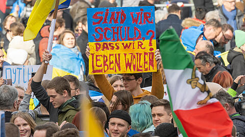 Ein junger Mann aus der Ukraine hält ein Transparent in der Menge hoch. Für ihn und seine Landsleute geht es ums pure Überleben.