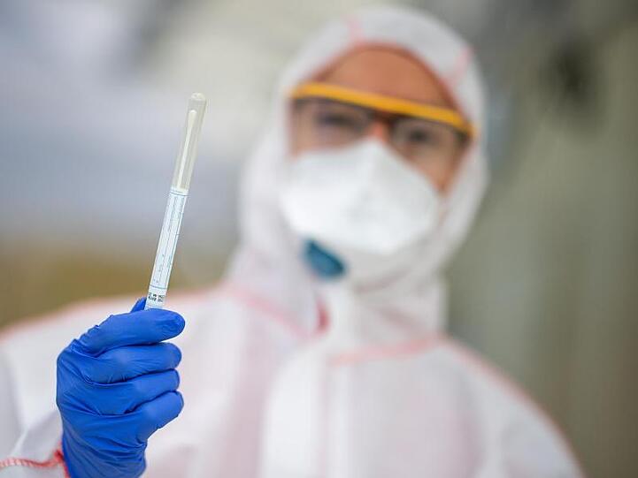 Ein Mitarbeiter hält in einem Abstrichzentrum einen Coronatest-Abstrich in der Hand. Foto: Sebastian Gollnow/dpa/Symbolbild