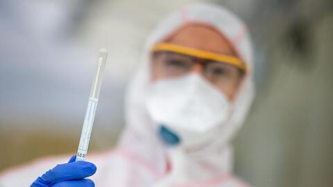 Ein Mitarbeiter hält in einem Abstrichzentrum einen Coronatest-Abstrich in der Hand. Foto: Sebastian Gollnow/dpa/Symbolbild