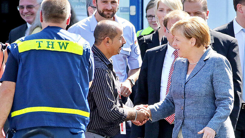 Bundeskanzlerin Angela Merkel (CDU, r) besucht eine Flüchtlingsunterkunft in Heidenau (Sachsen) und spricht mit einem der Helfer. Bundeskanzlerin Angela Merkel (CDU, r) besucht eine Flüchtlingsunterkunft in Heidenau (Sachsen) und spricht mit einem der Helfer.