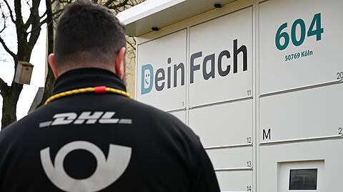 Ein DHL-Paketbote holt Sendungen aus einem DeinFach-Automaten.