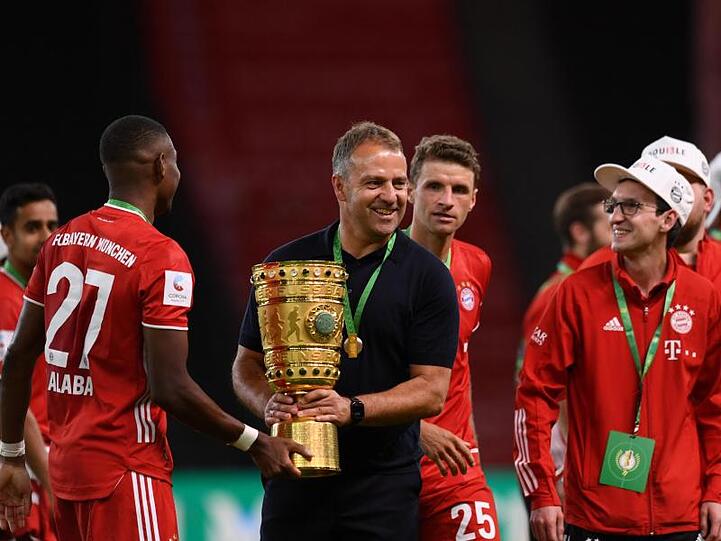 Münchens Trainer Hansi Flick jubelt mit der Trophäe nach dem Spiel. Foto: Annegret Hilse/Reuters/POOL/dpa