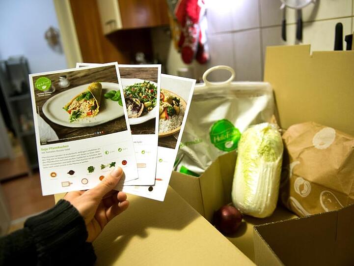 Ein Mann hält mitgelieferte Kochrezepte aus einer Hellofresh Kochbox in der Hand.