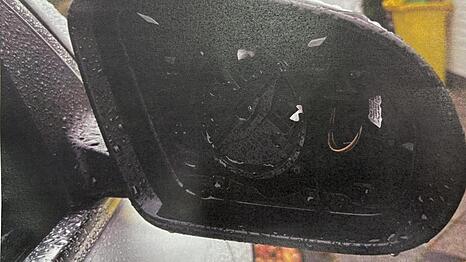 Ein ausgebauter Au&szlig;enspiegel an einem im Stadtgebiet am Stra&szlig;enrand abgestellten Auto.