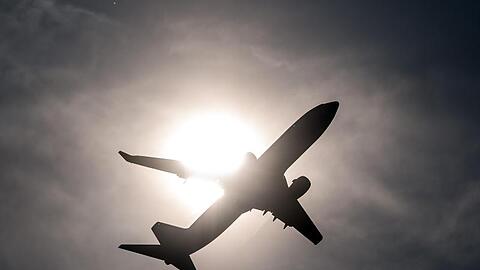 Ein Flugzeug startet und fliegt an der Sonne vorbei. Foto: Federico Gambarini/Archivbild