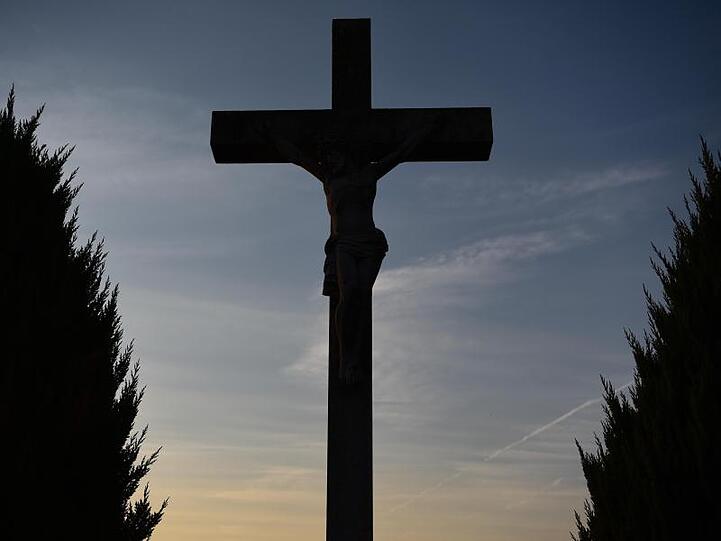 Ein Kreuz vor dem Abendhimmel. Foto: Nicolas Armer/dpa/Symbolbild