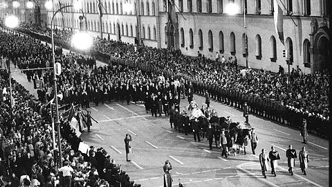 Der Trauerzug: Am 7. Oktober 1988 ziehen sechs Pferde die Lafette mit dem von einer Fahne bedeckten Sarg mit Franz Josef Strauß von der Residenz über den Odeonsplatz und die Ludwigstraße bis zum Siegestor. Über 100  000 Menschen verfolgen das Geschehen.