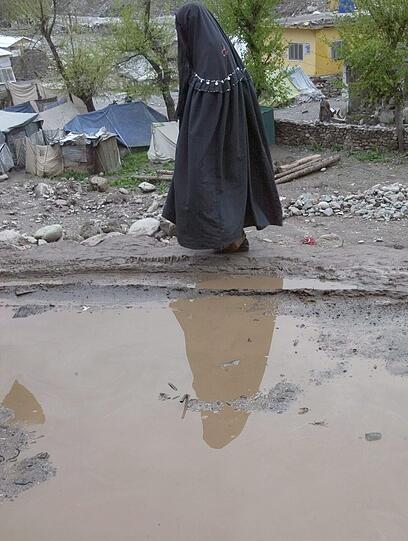 Ein Mann geht durch Matsch und Trümmer in Balakot in Pakistan - sechs Monate nach dem Erdbeben liegt noch viel in Trümmern.