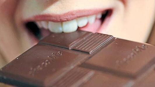 Eine Frau beißt in eine Tafel Schokolade. (Symbolbild) Eine Frau beißt in eine Tafel Schokolade. (Symbolbild)