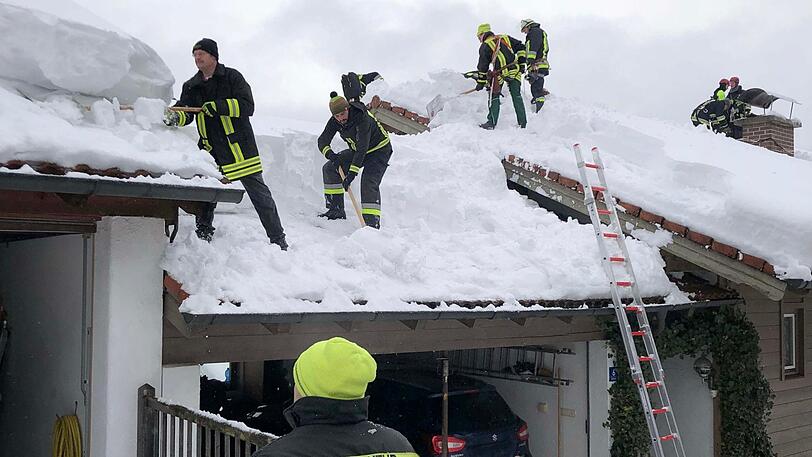 Helfer räumen ein Hausdach im Berchtesgadener Land.