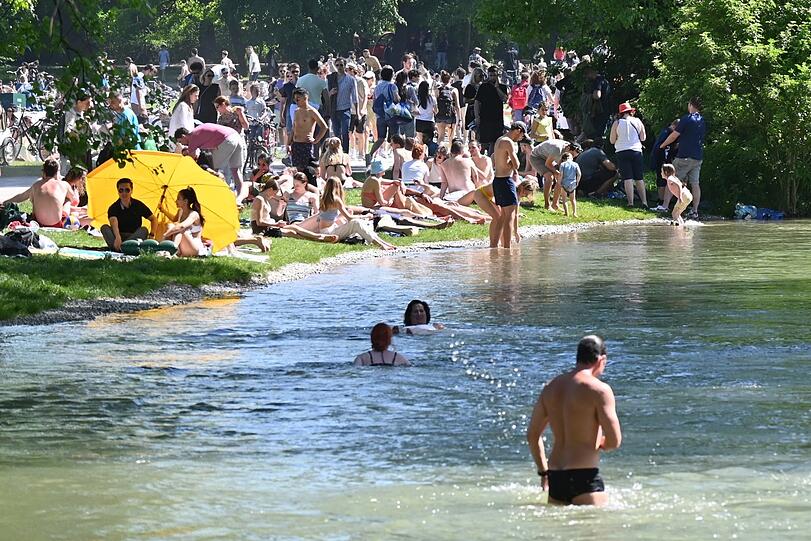 Zahlreiche Menschen genießen die Sonne im Englischen Garten am Eisbach. Doch der Bach hat auch mehrere Stellen, an denen das Baden lebensgefährlich ist.