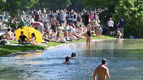 Zahlreiche Menschen genießen die Sonne im Englischen Garten am Eisbach. Doch der Bach hat auch mehrere Stellen, an denen das Baden lebensgefährlich ist.