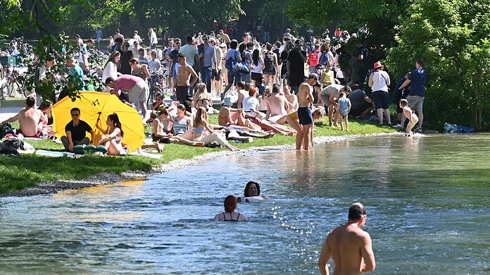 Zahlreiche Menschen genießen die Sonne im Englischen Garten am Eisbach. Doch der Bach hat auch mehrere Stellen, an denen das Baden lebensgefährlich ist.
