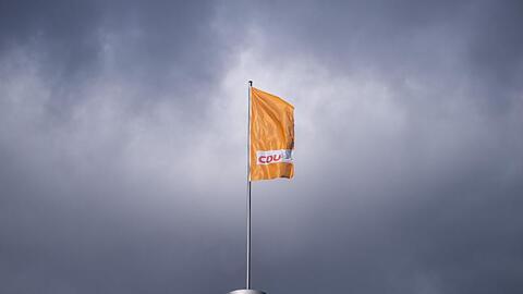 Die CDU-Fahne weht auf dem Konrad-Adenauer-Haus in Berlin - vor dunklen Wolken.
