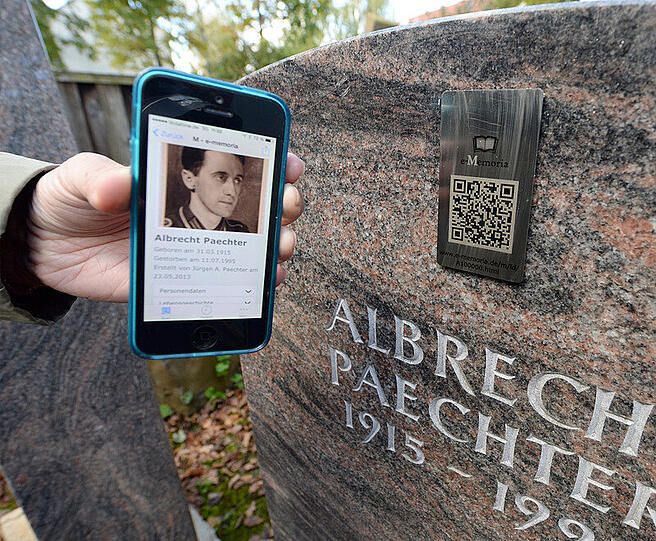 Auf einem Handy wird am 21.10.2014 in Weilimdorf (Baden-Württemberg) eine Trauerseite eines Verstorbenen angezeigt. Die Trauerseite wird über einen QR-Code auf einem Grabstein angesteuert. Foto: Bernd Weißbrod