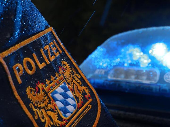 Ein Polizist steht im Regen vor einem Streifenwagen. Foto: Karl-Josef Hildenbrand/dpa/Archivbild