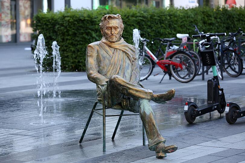 Hier sitzt Helmut Dietl - zwischen Wasserspiel und E-Scootern.