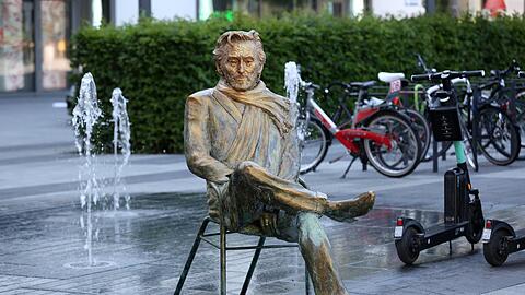 Hier sitzt Helmut Dietl - zwischen Wasserspiel und E-Scootern.