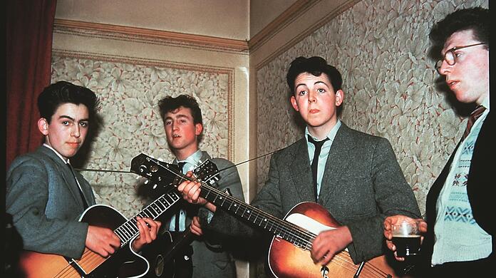 George Harrison (links), John Lennon und Paul McCartney 1958 bei Pauls Tante Jin in Liverpool. Der Zuhörer heißt Dennis und ist ein Freund von Tante Jins Sohn.