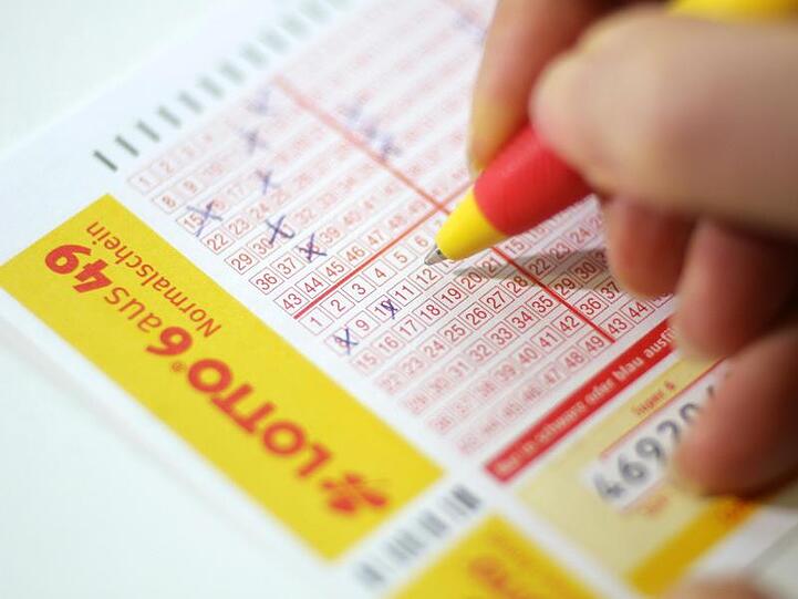 Eine Person hält einen Stift in der Hand und füllt einen Lotto-Schein aus. Foto: Jens Wolf/Archiv