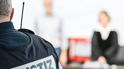 Ein Justizbeamter steht in einem Gerichtssaal. Foto: Sebastian Gollnow/dpa/Archivbild