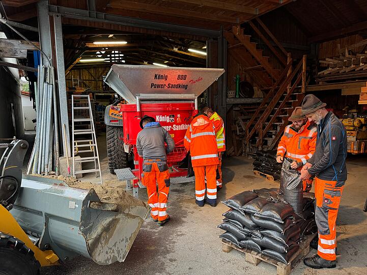 Mitarbeiter vom Bauhof in Aschau im Chiemgau füllen Sandsäcke. Im Chiemgau ist die Lage nach dem Dauerregen teils angespannt. In der Gemeinde Aschau (Landkreis Rosenheim) befüllten Einsatzkräfte Sandsäcke, weil das Grund- und Oberflächenwasser anstieg.