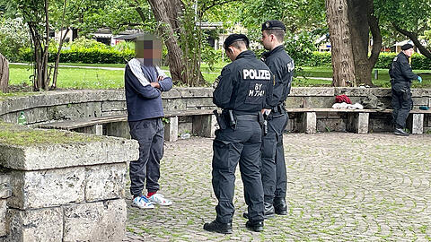 Polizeibeamte &uuml;berpr&uuml;fen die Personalien eines verd&auml;chtigen Mannes im Alten Botanischen Garten.