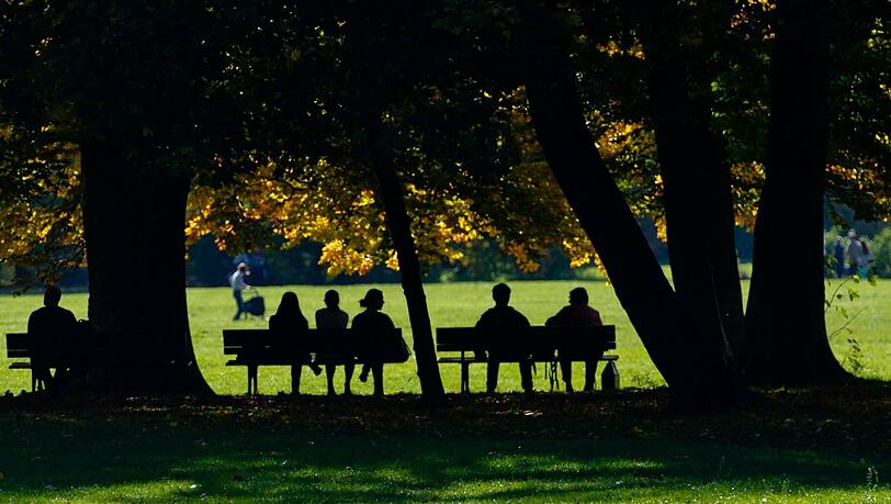 Menschen sitzen am Dienstag auf den Parkbänken im Englischen Garten. Menschen sitzen am Dienstag auf den Parkbänken im Englischen Garten.