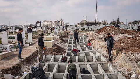 Syrer präparieren entlang der türkisch-syrischen Grenze Gräber für ihre Angehörigen, die bei dem verheerenden Erdbeben ums Leben gekommen sind.