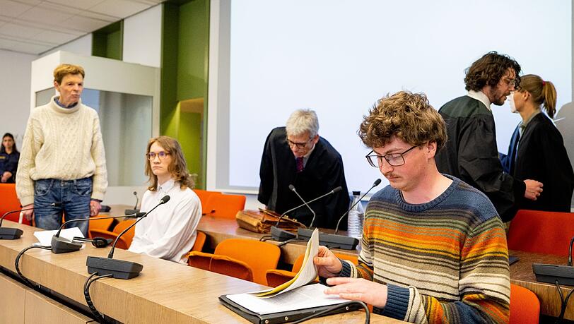 Die angeklagten Klimaaktivisten Michael Winter (l-r), Lukas Popp und Simon Lachner sitzen zum Prozessauftakt auf der Anklagebank.