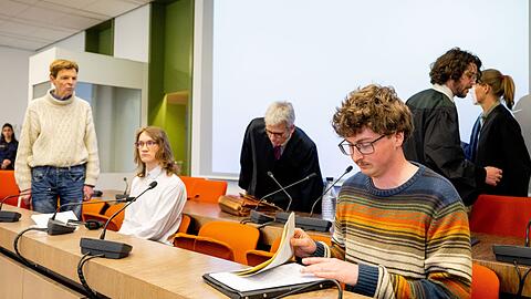 Die angeklagten Klimaaktivisten Michael Winter (l-r), Lukas Popp und Simon Lachner sitzen zum Prozessauftakt auf der Anklagebank.