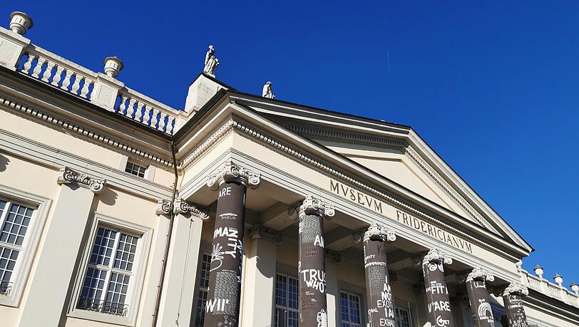 "From Virus to Virussia", also "Vom Virus zu Virussland" - der rumänische Künstler Dan Perjovschi hat die Säulen vor dem Fridericianum mit frechen Sprächen, Buchstaben, Strichmännchen, Friedenssymbolen und kleinen Zeichnungen gestaltet.
