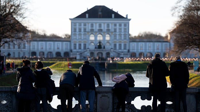 Ausflügler nutzen das schöne Wetter für einen Spaziergang am Nymphenburger Kanal. Im Hintergrund ist das Schloss Nymphenburg zu sehen.