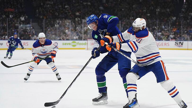 Vancouvers Tyler Myers (M) und Evander Kane von den Edmonton Oilers kämpfen um den Puck.
