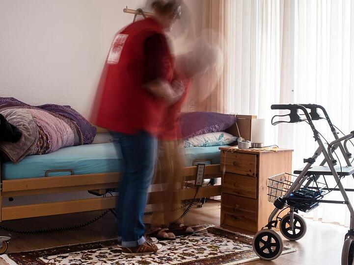 Eine Pflegerin hilft einer alten Frau beim Aufstehen aus ihrem Bett. Foto: Jana Bauch/Archiv