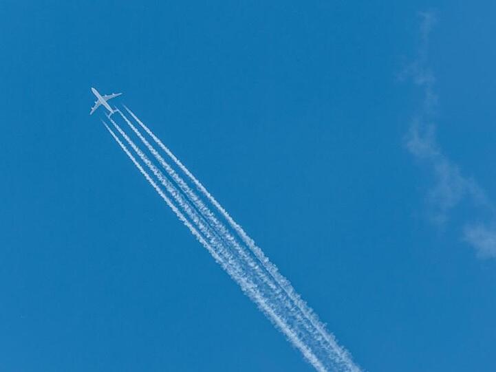 Ein Flugzeug zieht Kondensstreifen hinter sich her. Foto: Robert Michael/Archivbild