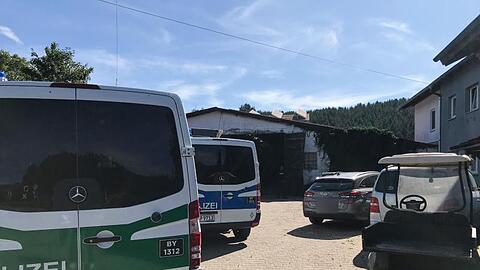 Polizeifahrzeuge stehen neben anderen Fahrzeugen auf einem Hof vor einem Stall im Allgäu. Foto: Benjamin Liss