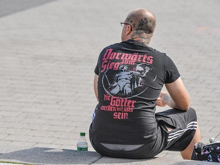 Ein Teilnehmer des Wahlkampfauftakts sitzt auf einer Treppe vor der Cottbusser Stadthalle.