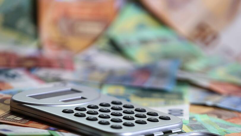 Ein Taschenrechner liegt auf verschiedenen Euro-Banknoten. (Symbolbild)