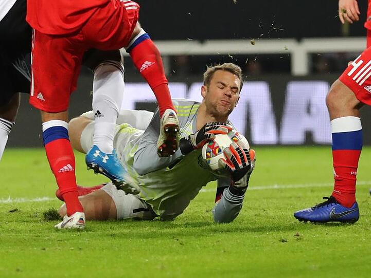 Torwart Manuel Neuer sichert den Ball vor zwei heranstürmenden Russen.