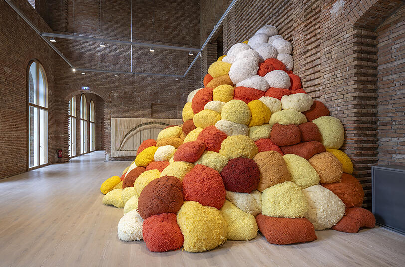Sheila Hicks Riesenarbeit „Saffron Sentinel“ von 2017 macht sich ganz fabelhaft in den unverputzten Räumen von Schloss Herrenchiemsee. Dahinter sieht man ein weiteres Werk der 92-jährigen Künstlerin.