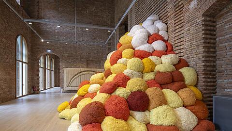 Sheila Hicks Riesenarbeit „Saffron Sentinel“ von 2017 macht sich ganz fabelhaft in den unverputzten Räumen von Schloss Herrenchiemsee. Dahinter sieht man ein weiteres Werk der 92-jährigen Künstlerin.