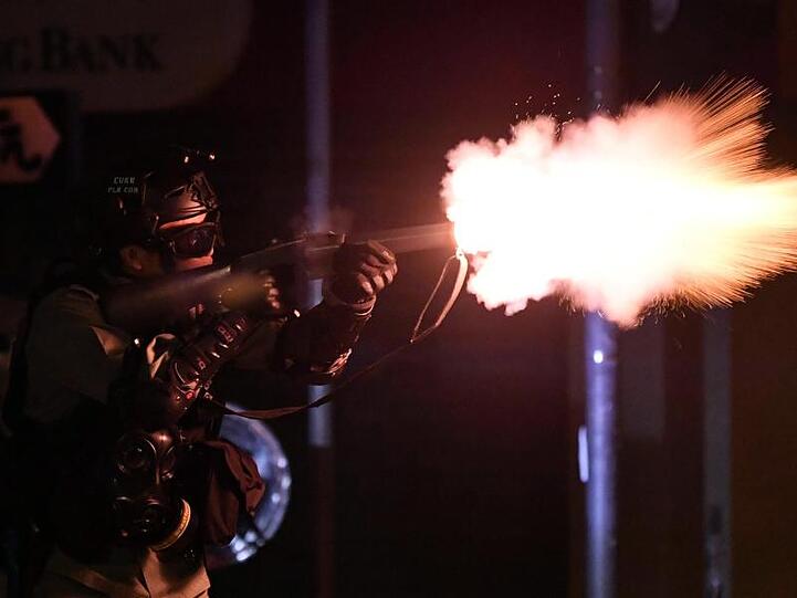 Ein Polizist schießt Tränengas auf Demonstranten.