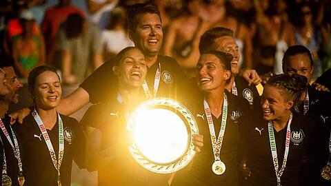 Der Moment des Triumphes: Nationaltrainer Alexander Novakovic (hinten Mitte) mit Physiotherapeutin  Franziska Stadler, Lucie-Marie Kretzschmar (Minga Turtles Ismaning; Tochter von Ex-Handball-Nationalspieler Stefan Kretzschmar; die EM-Trophäe in der Hand);  Amelie Bayerl (Brüder Ismaning), Kirsten Walter (Brüder Ismaning - vorne von links) sowie Co-Trainer Hendrik Sander (rechts neben Novakovic).